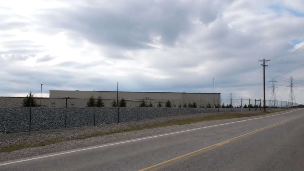 AI-generated illustration of an industrial perimeter beside utility lines, a road and parked cars.