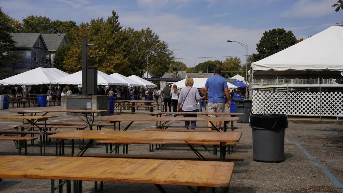 AI-generated illustration of picnic tables and temporary tents at an outdoor community event.