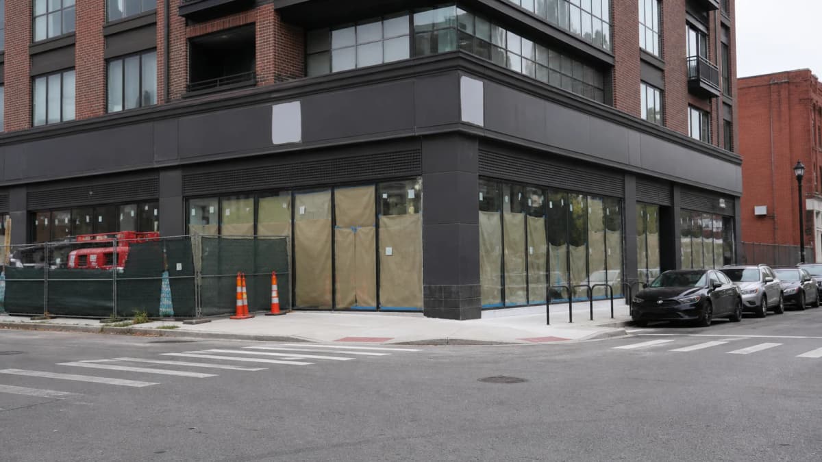 AI-generated illustration of a vacant ground-floor retail space below apartments at an urban intersection.