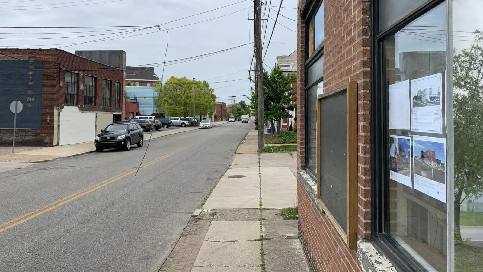 Street-level view of a Columbus commercial corridor showing older light-industrial buildings and surface parking lots — the type of property affected by Zone In Phase 2's proposed new zoning districts.