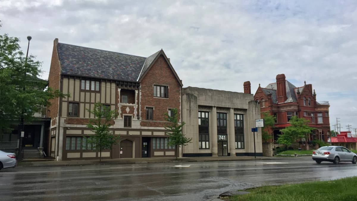 Archival photograph of older buildings and a wet sidewalk on East Broad Street in Olde Towne East, Columbus.